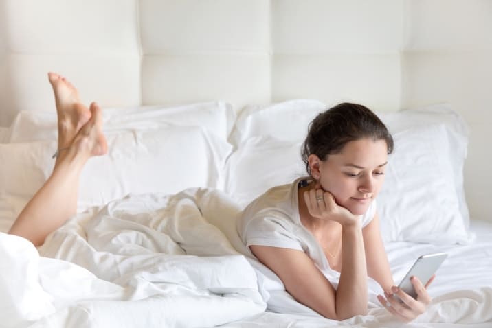 Woman using phone on bed