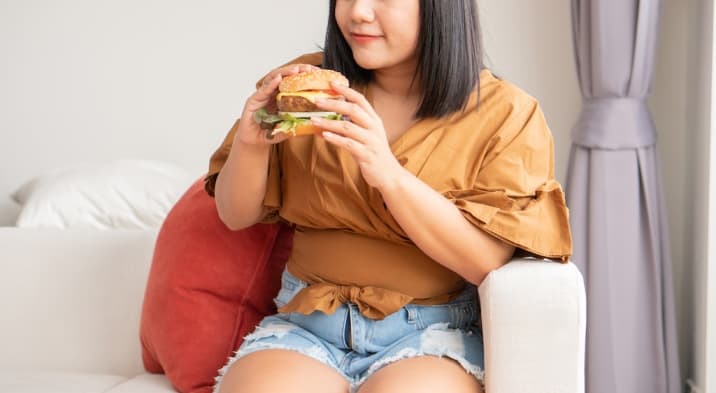 a woman eating junk food - toxic thing to remove from life- unhealthy habits