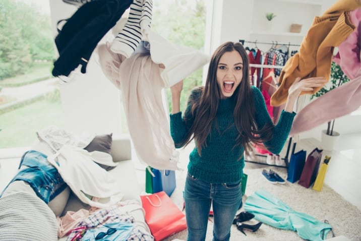 a woman standing amidst cloth clutter