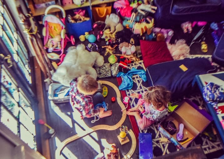 Two kids playing amidst many toys