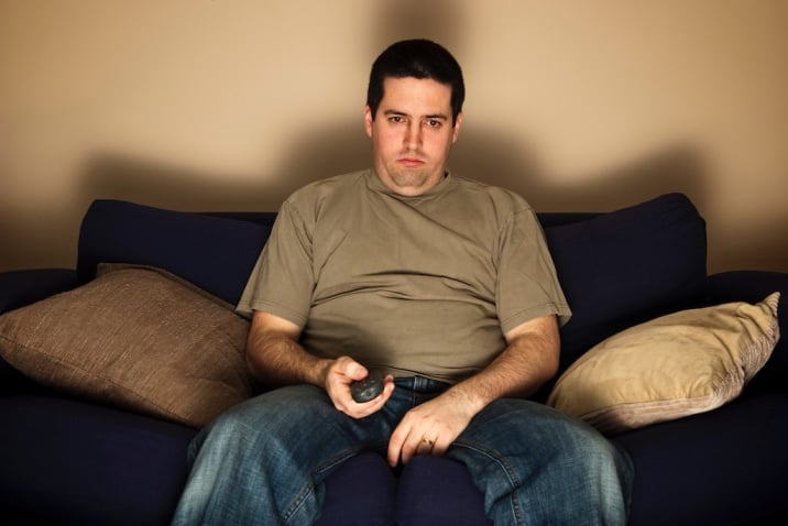 man sitting on couch watching TV - how to stop being a couch potato